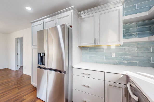 kitchen featuring white cabinets, appliances with stainless steel finishes, tasteful backsplash, and wood-type flooring