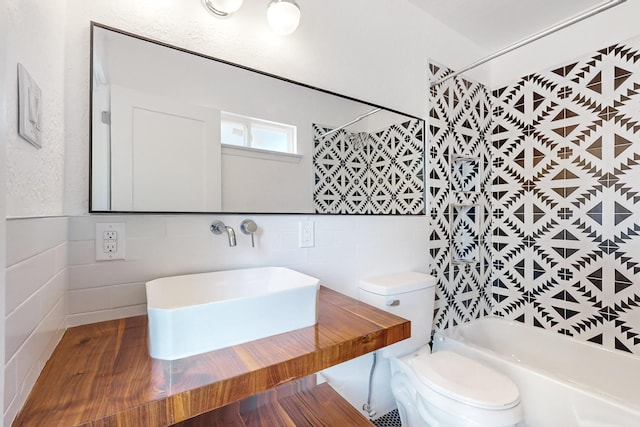 full bathroom featuring shower / tub combination, sink, tile walls, and toilet