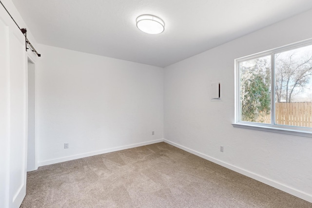 carpeted spare room featuring a barn door