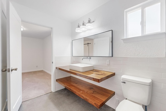 bathroom featuring vanity, toilet, and tile walls