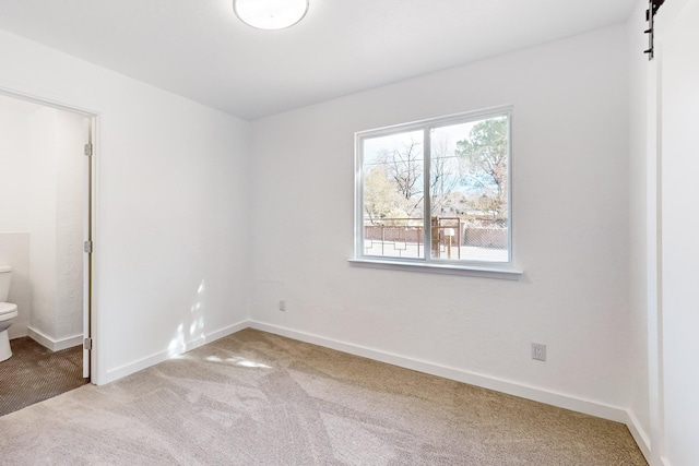 carpeted spare room with a barn door