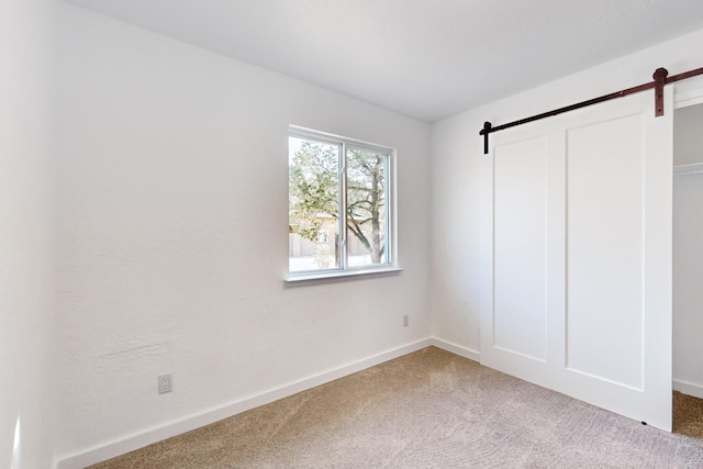 unfurnished bedroom featuring a barn door and carpet floors