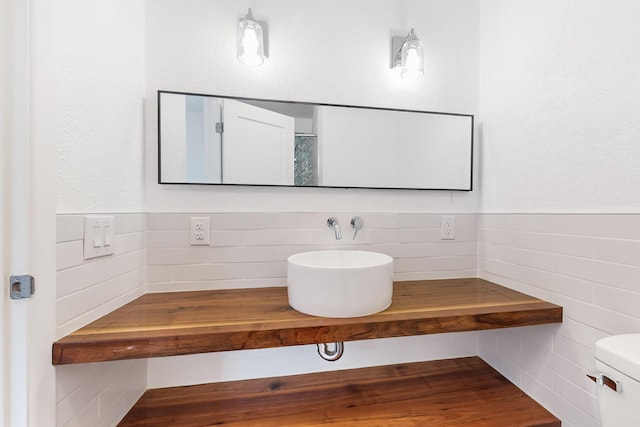 bathroom with sink, toilet, and tile walls