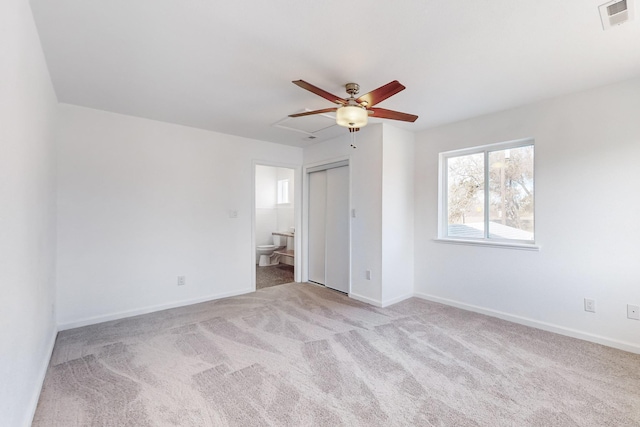 unfurnished bedroom featuring light carpet, ensuite bathroom, and ceiling fan