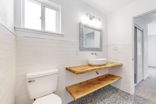 bathroom featuring sink, tile walls, and toilet