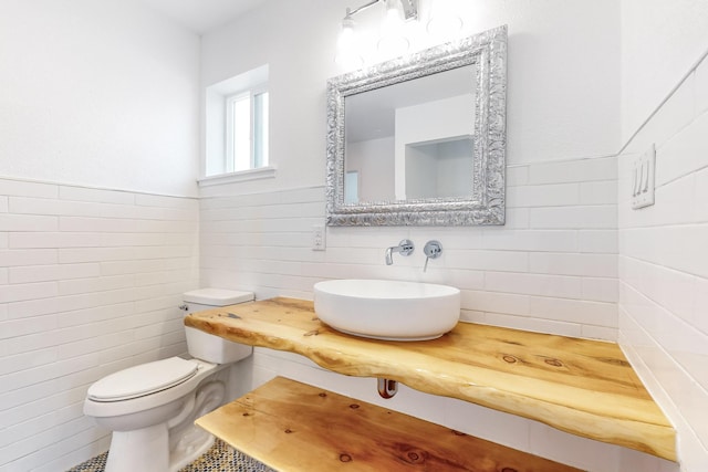 bathroom featuring toilet, sink, and tile walls