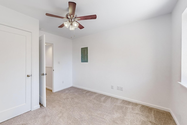 unfurnished bedroom with electric panel, ceiling fan, and light colored carpet