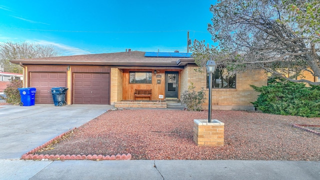 single story home with solar panels and a garage