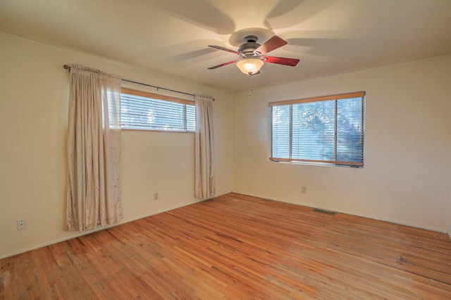 empty room featuring plenty of natural light, light hardwood / wood-style floors, and ceiling fan