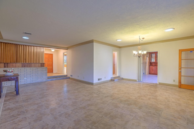 unfurnished living room featuring a textured ceiling, an inviting chandelier, and ornamental molding