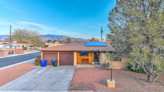 single story home featuring solar panels, a garage, and a mountain view