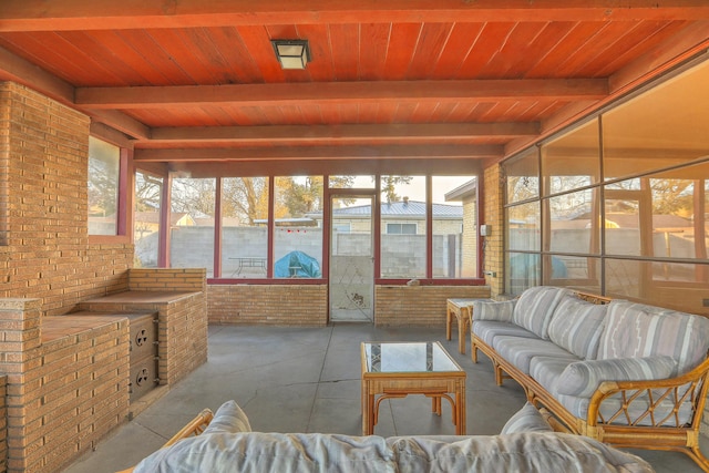 sunroom / solarium featuring beam ceiling, plenty of natural light, and wood ceiling