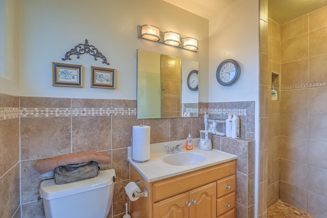 bathroom with vanity, toilet, tile walls, and a tile shower