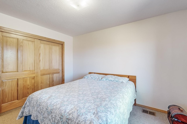 bedroom with a closet, carpet floors, and a textured ceiling