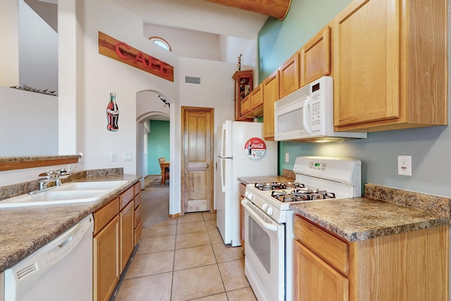 kitchen with light tile patterned floors, white appliances, light brown cabinetry, and sink