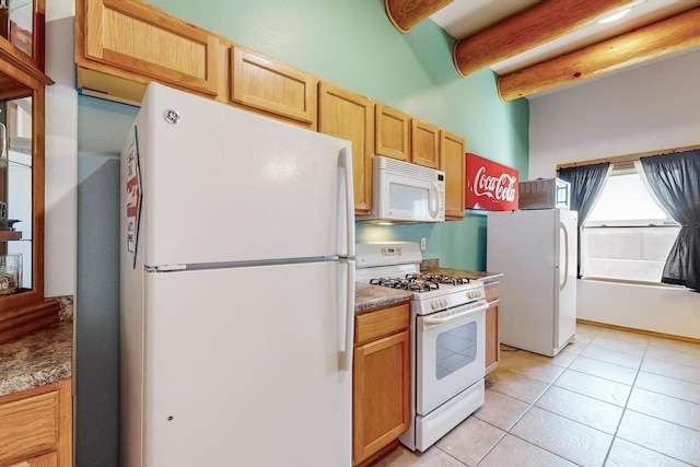 kitchen with beam ceiling, white appliances, light brown cabinetry, and light tile patterned flooring