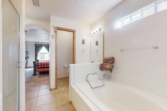 bathroom with a tub, a wealth of natural light, tile patterned flooring, and vanity