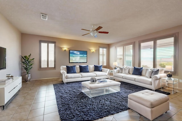 living area featuring visible vents, ceiling fan, a textured ceiling, and light tile patterned floors