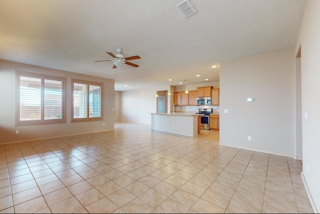 unfurnished living room with ceiling fan, sink, light tile patterned floors, and a textured ceiling