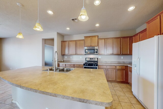 kitchen with hanging light fixtures, stainless steel appliances, a kitchen island with sink, and sink