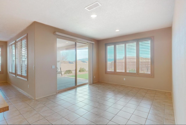 spare room with light tile patterned floors, baseboards, visible vents, a textured ceiling, and recessed lighting