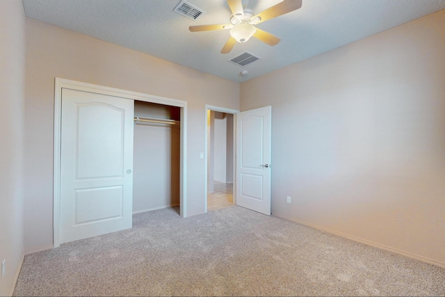 unfurnished bedroom featuring ceiling fan, light colored carpet, and a closet