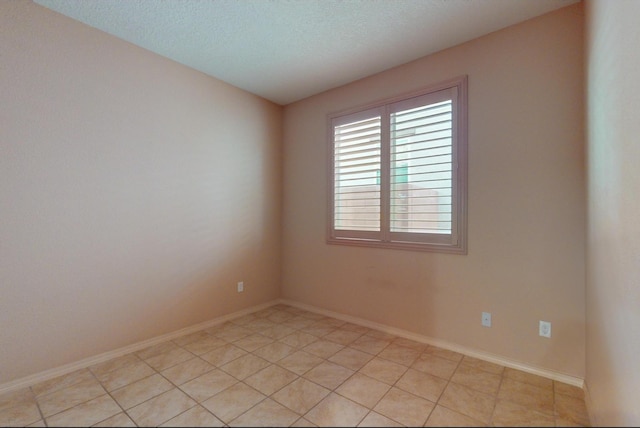 unfurnished room featuring a textured ceiling, baseboards, and light tile patterned floors