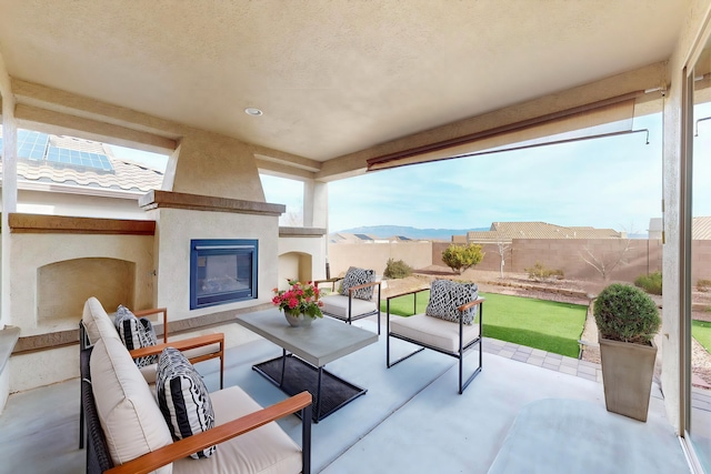 view of patio / terrace with an outdoor living space with a fireplace, a mountain view, and a fenced backyard