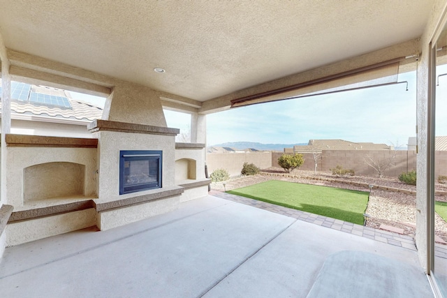 view of patio / terrace featuring a fenced backyard, a glass covered fireplace, and a mountain view