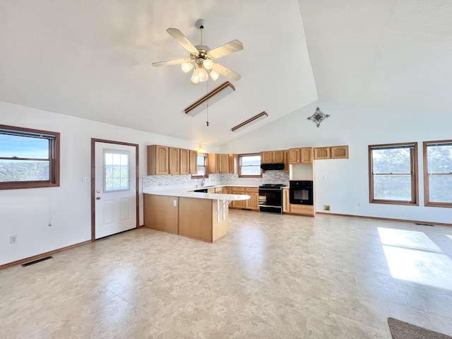 kitchen with ceiling fan, black range oven, range hood, kitchen peninsula, and a kitchen bar