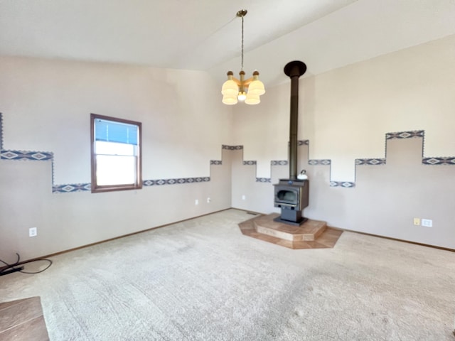 unfurnished living room featuring carpet flooring, a chandelier, a wood stove, and vaulted ceiling