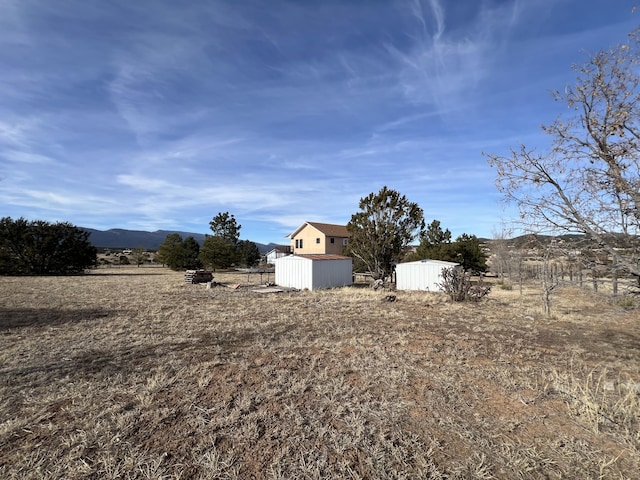 view of yard featuring a mountain view, a storage unit, and a rural view