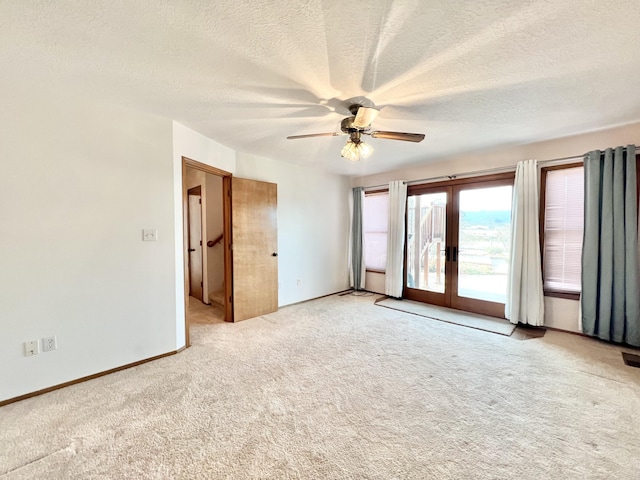 carpeted empty room featuring french doors, a textured ceiling, and ceiling fan