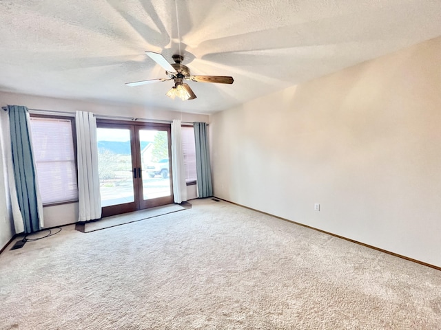 carpeted empty room featuring french doors, a textured ceiling, and ceiling fan