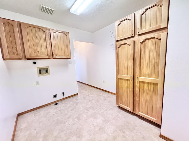 clothes washing area with washer hookup, electric dryer hookup, cabinets, and a textured ceiling