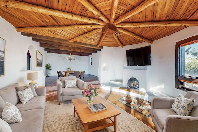 living room with a notable chandelier, beam ceiling, light wood-type flooring, and wood ceiling