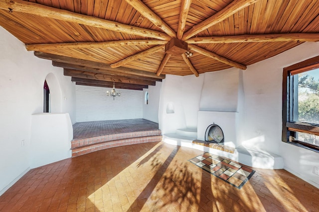 unfurnished living room with beamed ceiling, a notable chandelier, and wooden ceiling