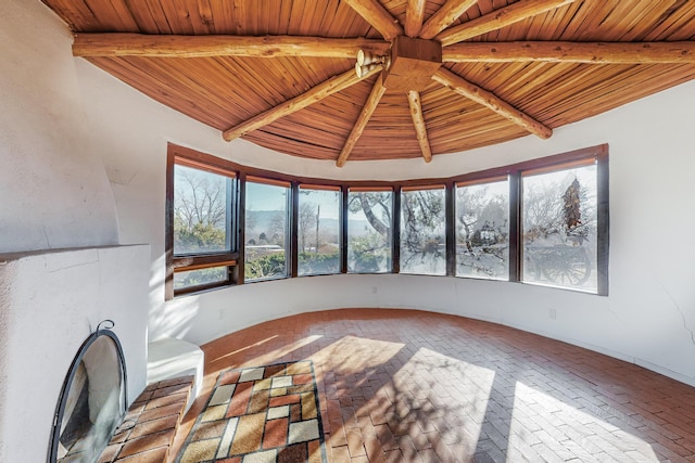 unfurnished living room with a wealth of natural light, beamed ceiling, and wooden ceiling