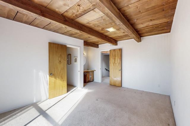 empty room with beam ceiling, wood ceiling, and light carpet