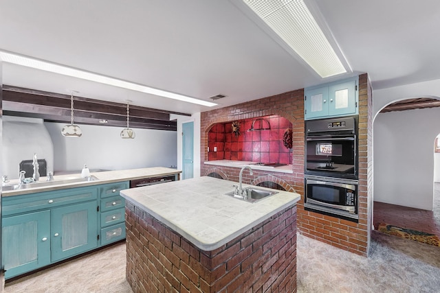 kitchen featuring sink, decorative light fixtures, light colored carpet, and an island with sink