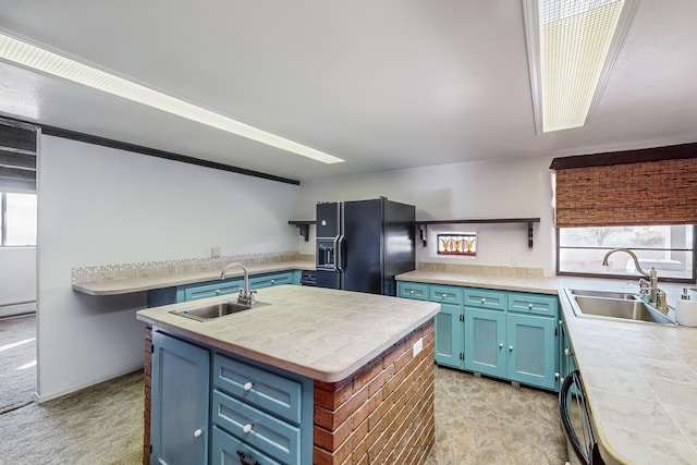 kitchen with light colored carpet, sink, blue cabinetry, an island with sink, and black fridge with ice dispenser