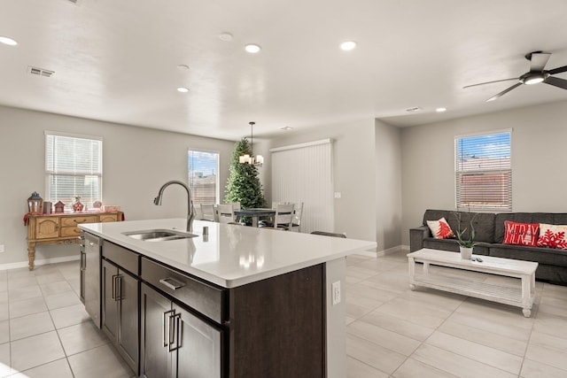 kitchen featuring pendant lighting, dishwasher, sink, dark brown cabinets, and a center island with sink