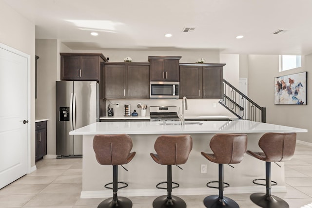 kitchen featuring an island with sink, appliances with stainless steel finishes, sink, and dark brown cabinetry