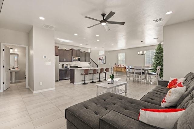 tiled living room with ceiling fan with notable chandelier