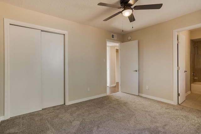 unfurnished bedroom with carpet flooring, ceiling fan, a textured ceiling, connected bathroom, and a closet