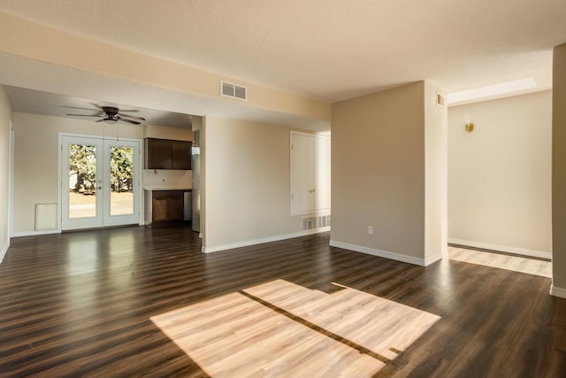 unfurnished living room with ceiling fan, dark hardwood / wood-style flooring, a textured ceiling, and french doors