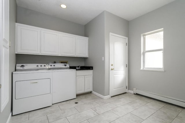 clothes washing area with cabinets, a baseboard heating unit, sink, light tile patterned floors, and washing machine and dryer