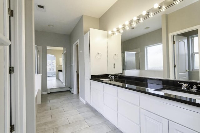 bathroom with tile patterned flooring, vanity, walk in shower, and a baseboard heating unit