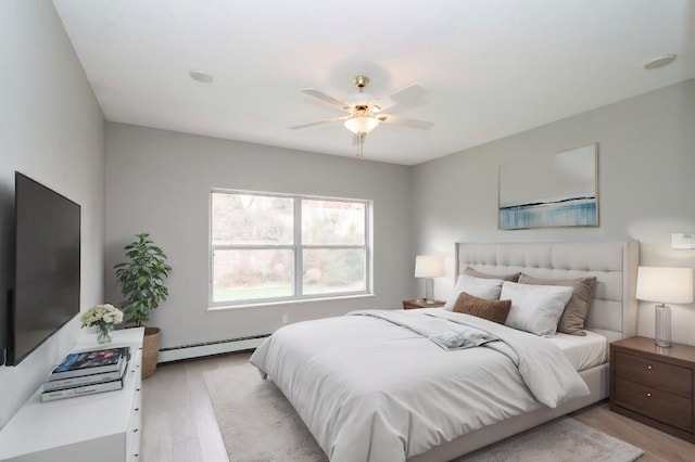 bedroom with light hardwood / wood-style flooring, baseboard heating, and ceiling fan