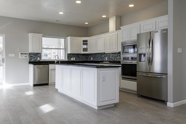 kitchen with appliances with stainless steel finishes, light wood-type flooring, sink, a center island, and white cabinetry